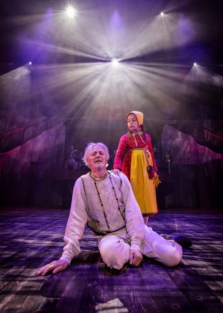 Foto från Västanå Musik & Teaters föreställning Kejsarn av Portugallien efter Selma Lagerlöfs roman, föreställande Kejsarn, spelad av Rolf Decerlund, och hans drömflicka Klara Gulla. Kejsaren sitter ner och ser förtvivlad ut. Drömflickan står bakom honom.