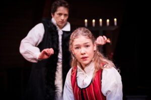 I Västanå Musik & Teaters föreställning Tiggarfolk & Herrskap, får du möta berättelser från flera av Selma Lagerlöfs verk som kretsar runt Lövdala. Förebilden är Selmas eget barndomshem Mårbacka. På bilden en kvinna med långt ljust hår. I bakgrunden en man med vit skjorta och svart lång väst.